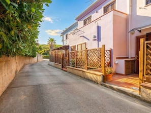 A narrow street with a row of houses, wooden fences, and a potted plant.