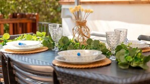 A table set outdoors with clear glassware, woven placemats, and a decorative vase with dried flowers. - Beautiful apartment for 6 people with terrace and pets allowed (Stintino)