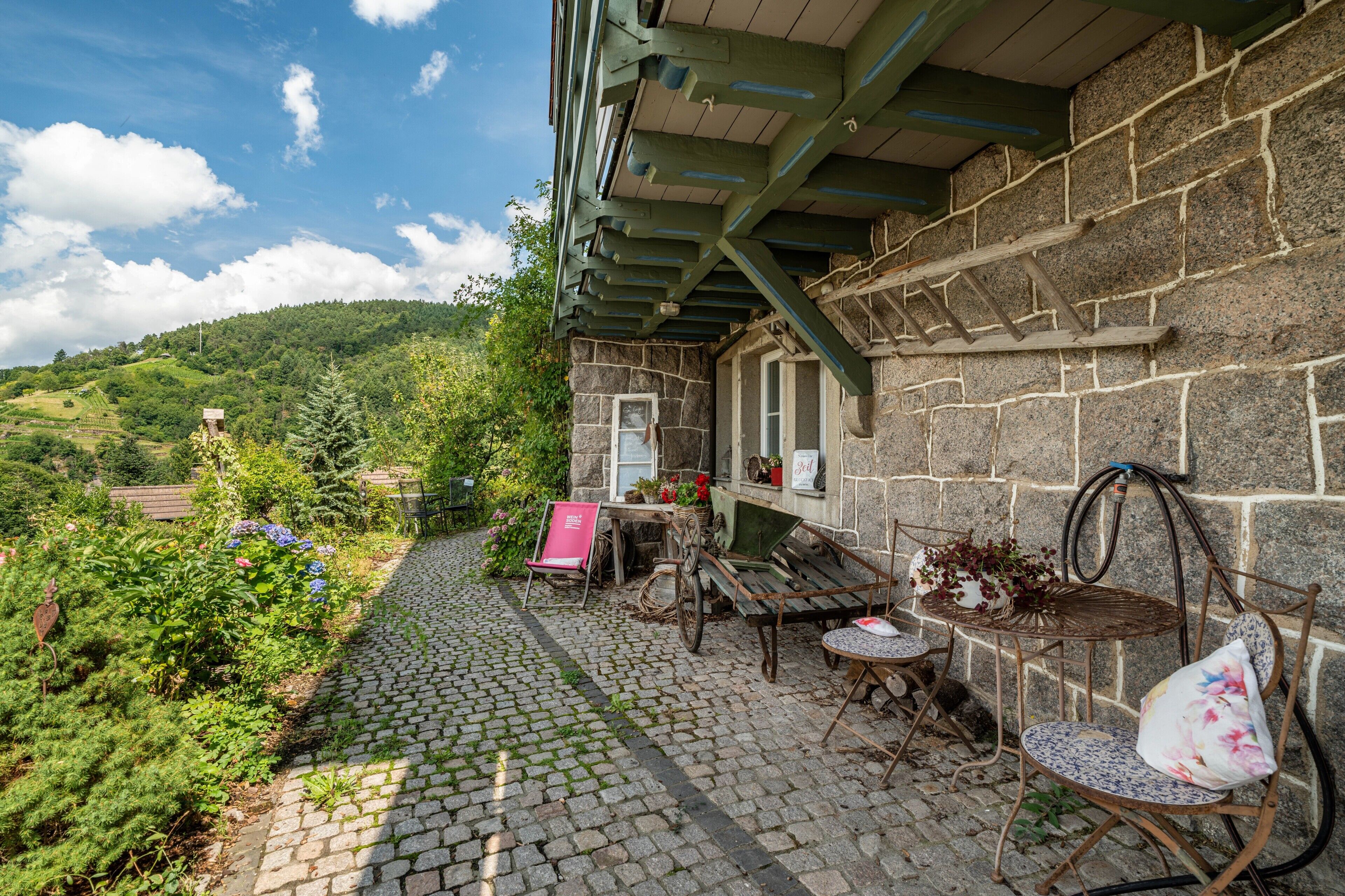 Un bâtiment en pierre doté d’un patio couvert, d’un espace extérieur aménagé pour s’asseoir et offrant une vue sur un paysage verdoyant.