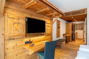 Un interior de fusta amb televisió de pantalla plana, escriptori de fusta, una panxa i un llit.