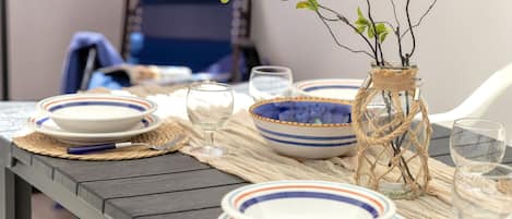 A dining table set with plates, bowls, and a glass vase with branches.