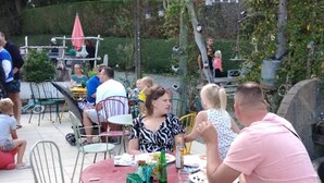 Un espace extérieur aménagé en terrasse, avec des tables et des chaises rondes, entouré de verdure.