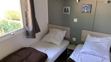 Una habitación con dos camas individuales, una ventana con cortina y un estante en la pared con un par de zapatos y un cuadro.