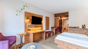Une pièce comprenant un bureau en bois, un lit, une télévision et une petite table avec un bol.