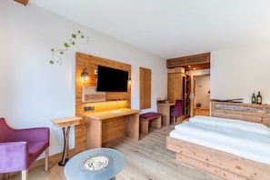 Ein Zimmer mit einem Holztisch, einem Bett, einem Fernseher und einem kleinen Tisch mit einer Schüssel.