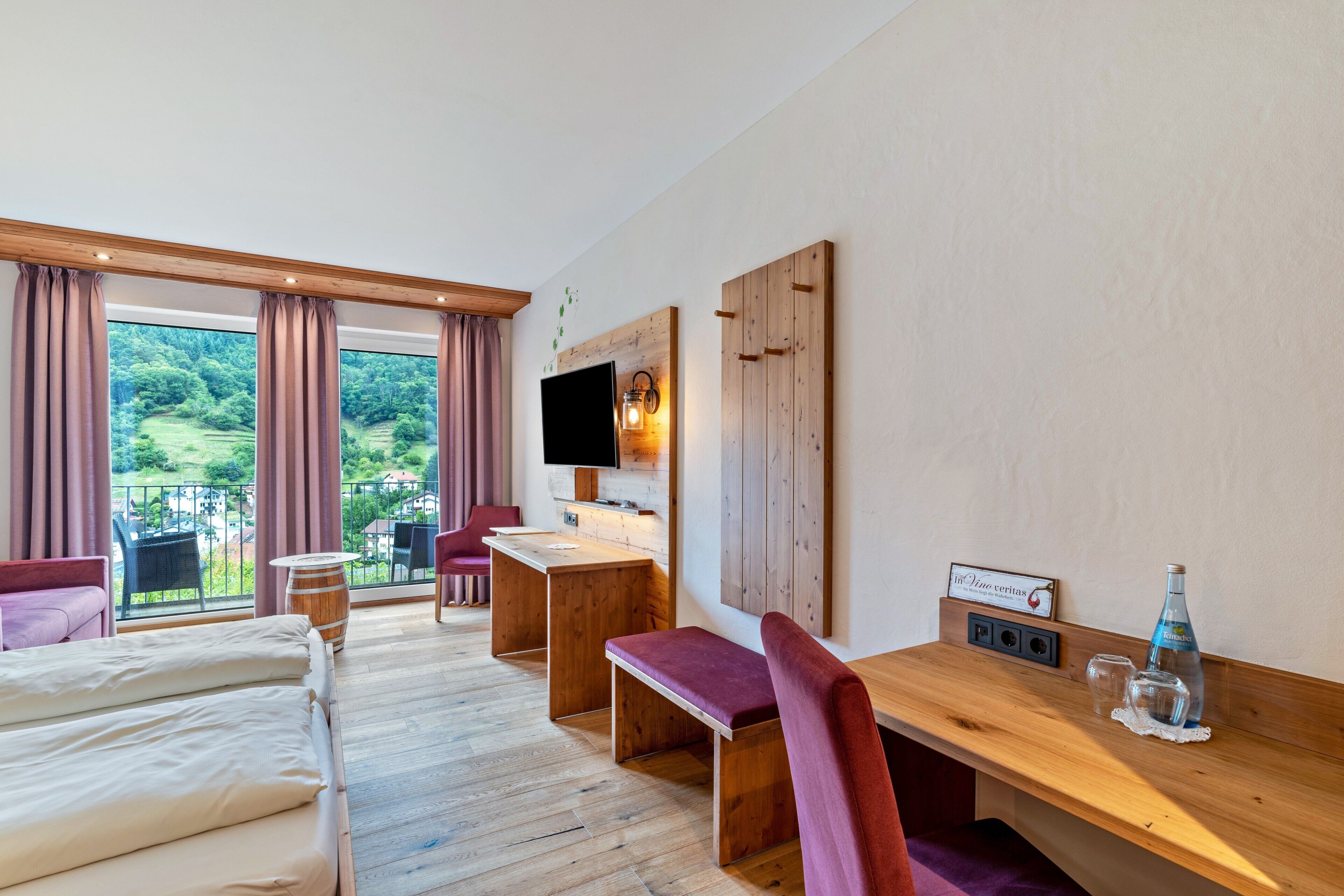 Une chambre d’hôtel équipée d’un lit, d’un bureau, d’une banquette, d’une télévision et offrant une vue sur l’extérieur.