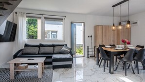Ein modernes Wohnzimmer mit Sofa, Couchtisch und Essbereich mit Stühlen und einem Tisch.