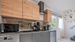 Eine moderne Küche mit Holzschränken, einem eingebauten Geschirrspüler und einem großen Fenster.