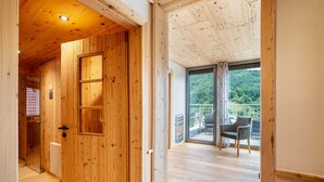 Een houten interieur met een schuifglazen deur die leidt naar een balkon met een stoel.