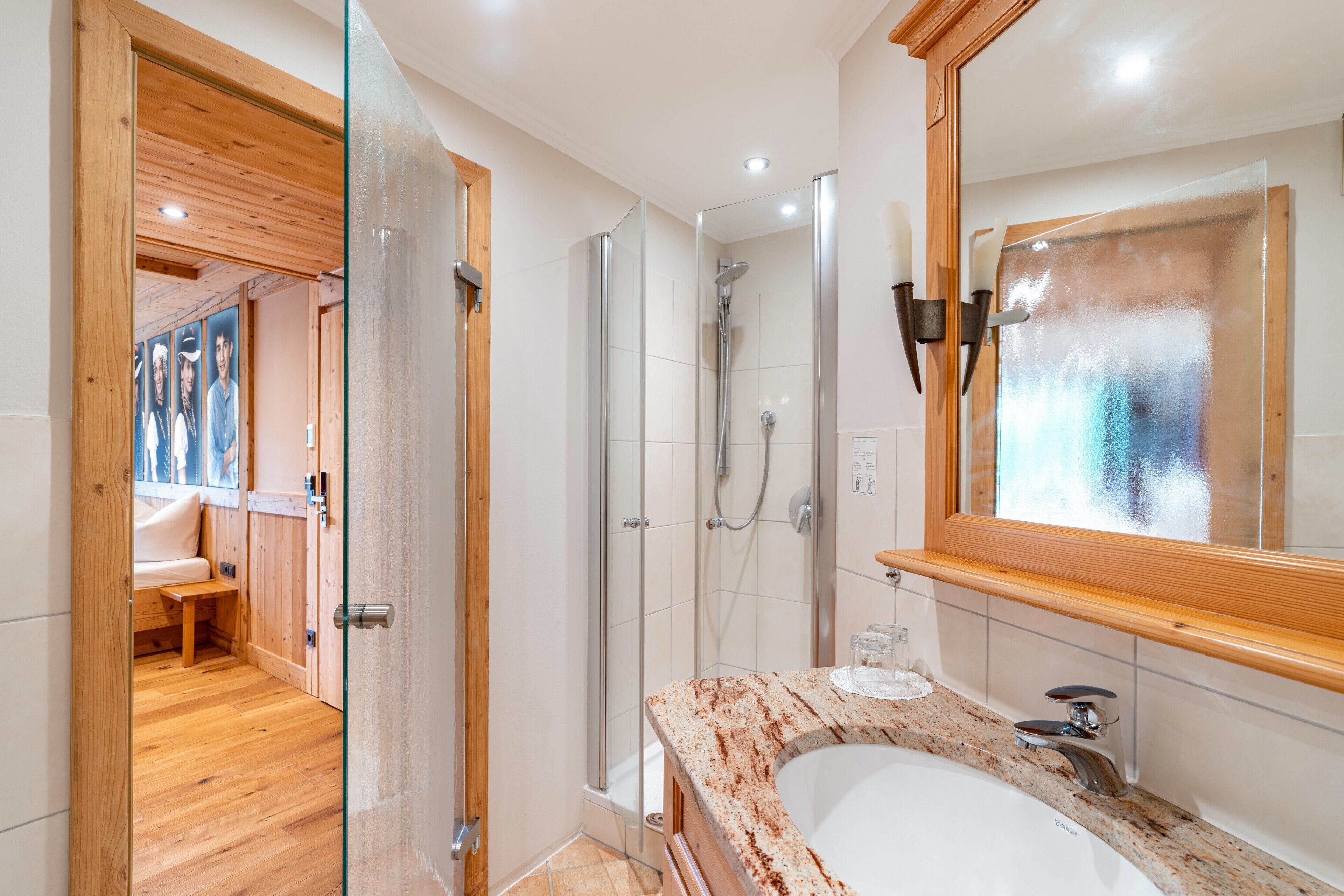 Un baño moderno con cabina de ducha de vidrio, tocador de madera y un espejo grande.
