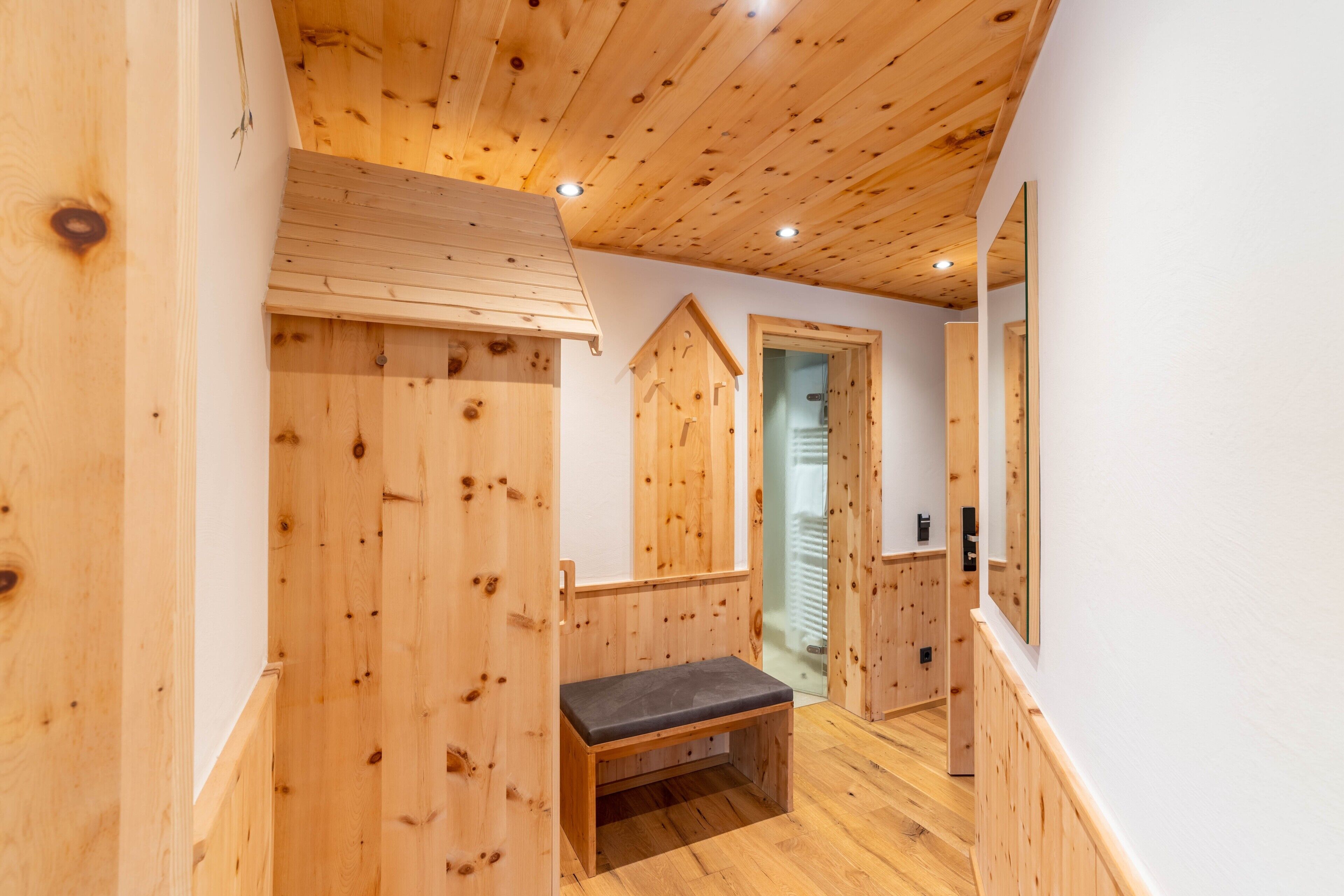 A wooden interior with a bench, wooden walls, and a staircase.