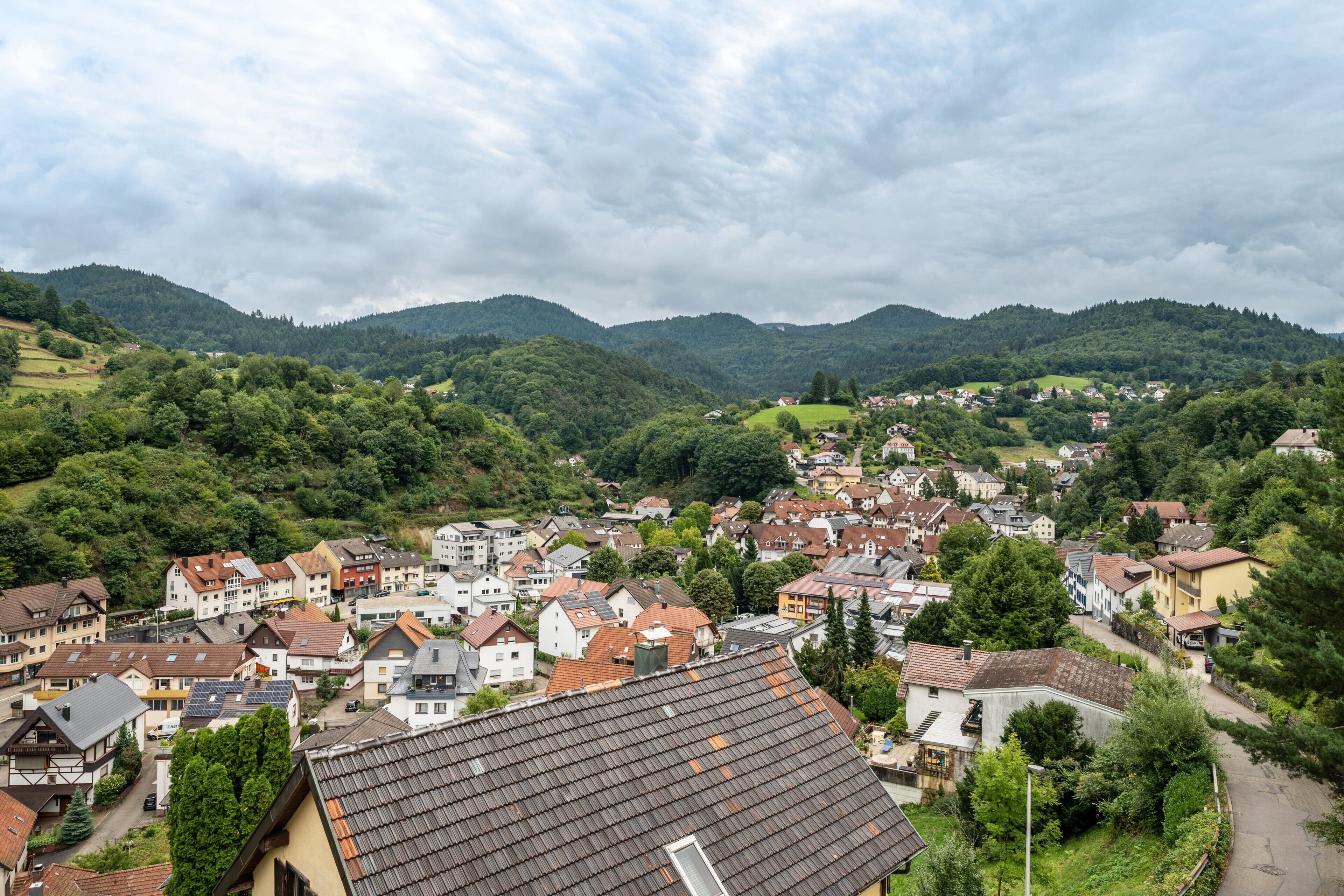 A town with a mix of traditional and modern buildings, surrounded by lush green hills.