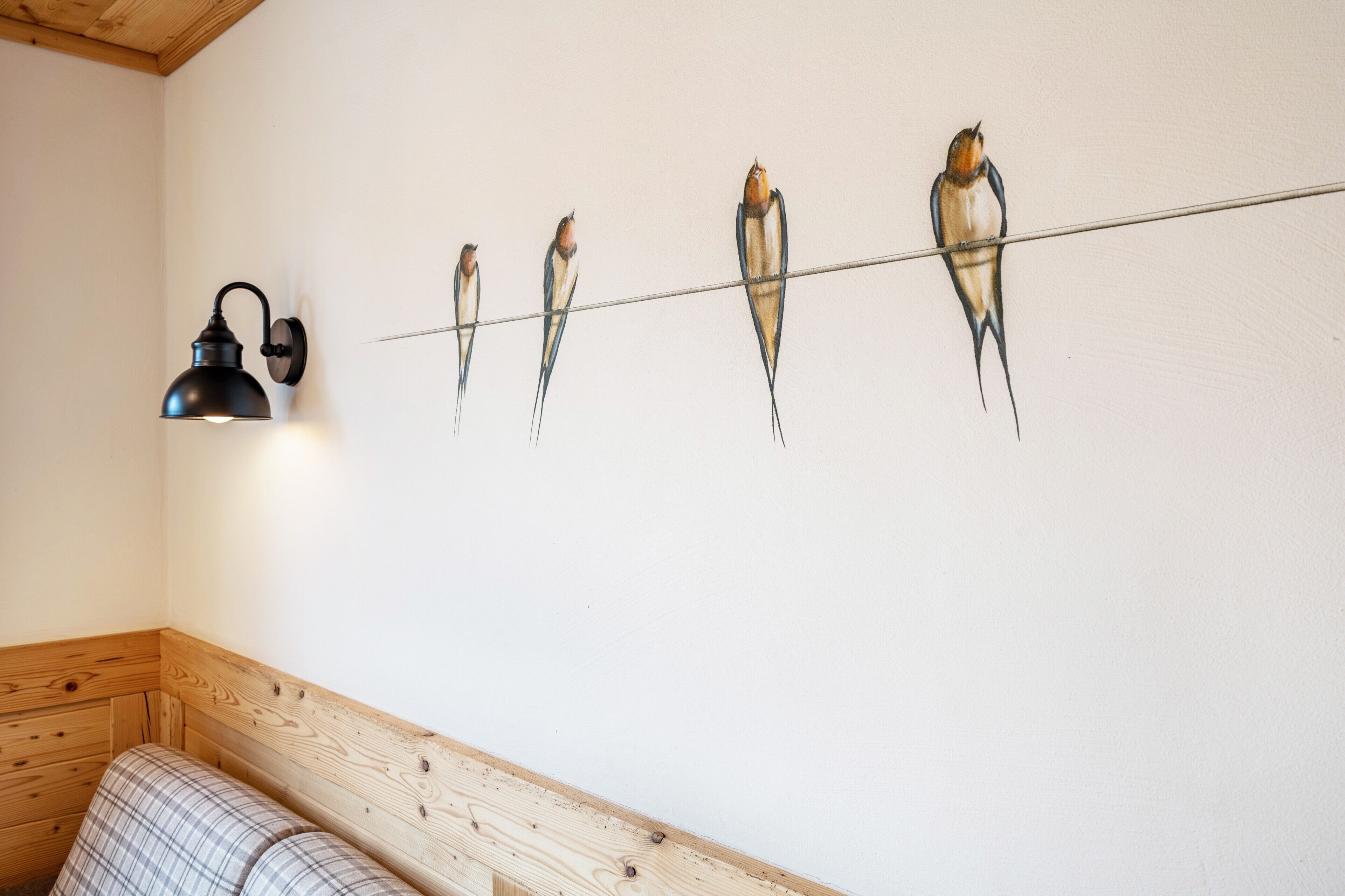 A wall with a row of bird paintings and a lamp.