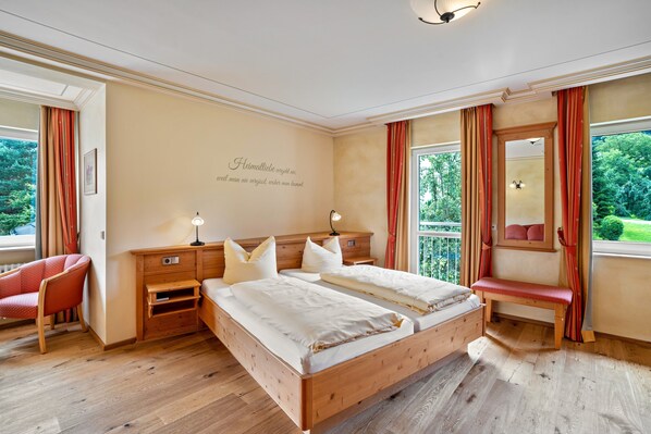 Ein Schlafzimmer mit einem großen Bett, Nachttischen, einem Sessel und einem Fenster mit Vorhängen.
