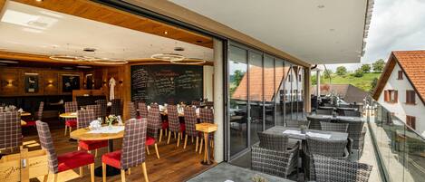 A restaurant with wooden flooring, checkered chairs, and a chalkboard menu.