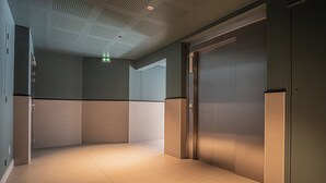 An elevator area with a modern design, featuring a metallic elevator door and a light-colored tiled floor. - Prestige Apartment & Cathedral View (Reims)