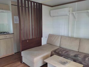 A compact living space with a kitchenette, a sofa, and an air conditioning unit. - 32m² Mobile Home with Terrace for 4 People in Anduze (Anduze)
