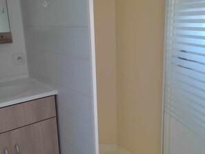 A bathroom with white tiles, a wooden cabinet, and a window with blinds. - 32m² Mobile Home with Terrace for 4 People in Anduze (Anduze)