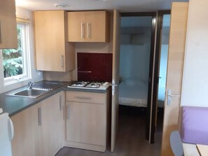 A compact kitchen with a gas stove, a sink, and wooden cabinets.