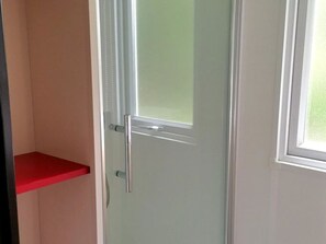 A door with a frosted glass panel, a red shelf, and a white frame.