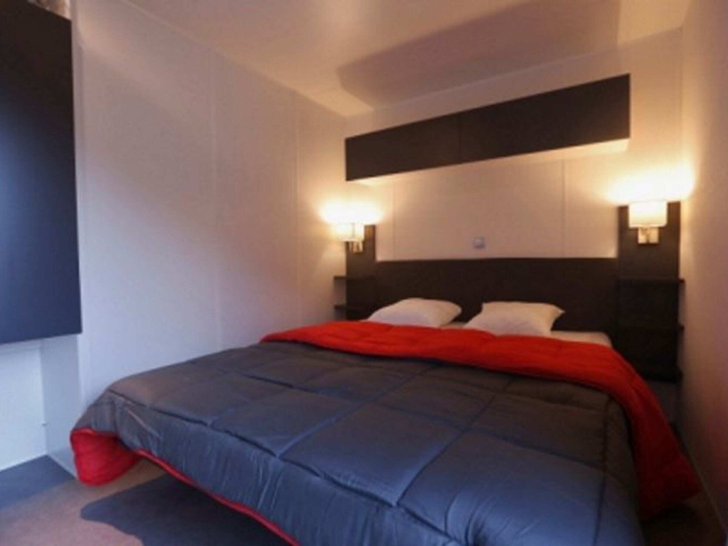 Een moderne hotelkamer met een groot bed, twee bedlampen en een flatscreen televisie aan de muur.