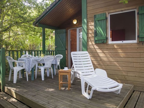 A wooden deck with outdoor furniture, including a table and chairs, and a lounge chair.