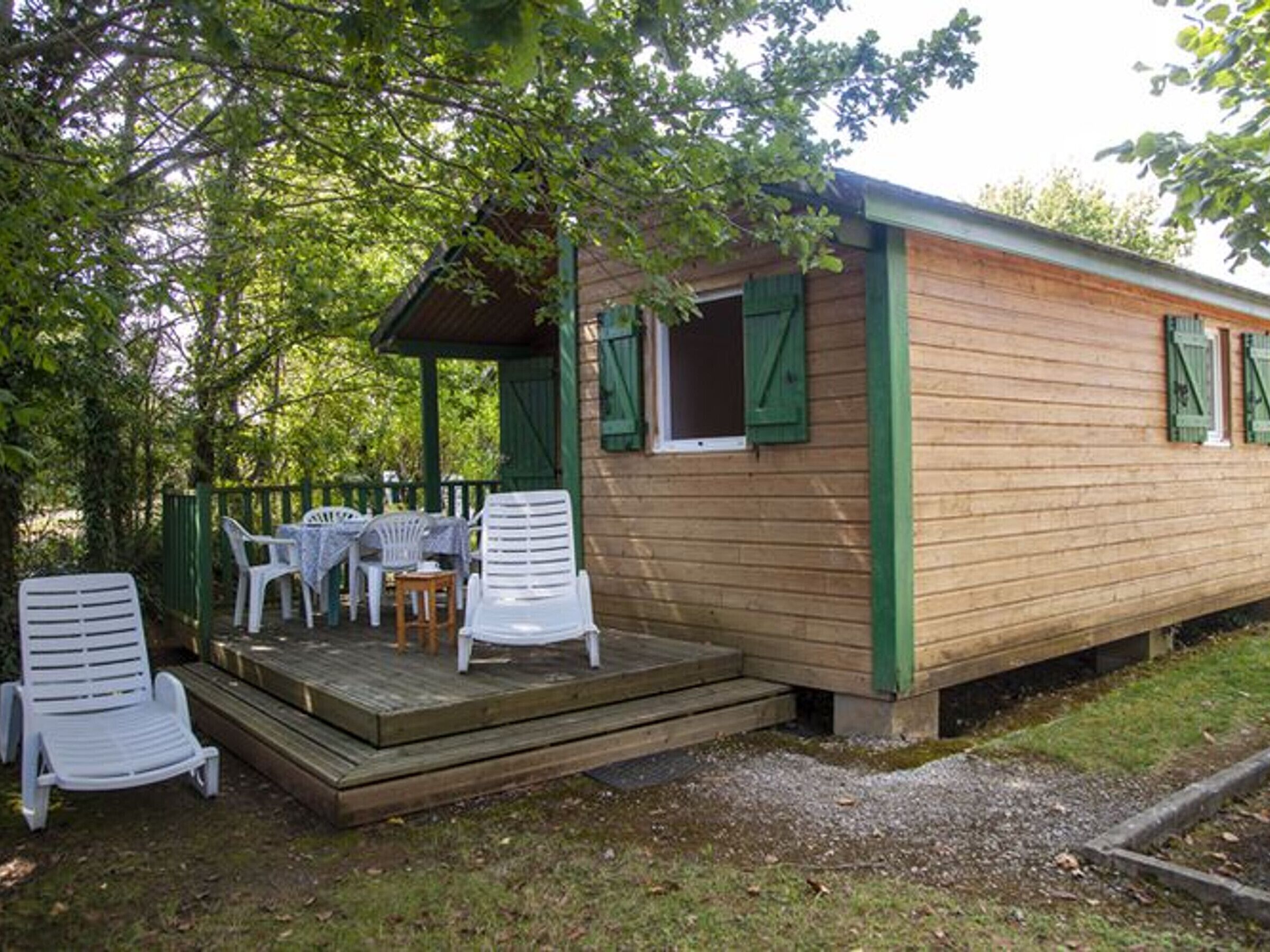 Una cabaña de madera con un porche, mobiliario exterior y un camino de grava.