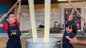 Two individuals in aprons working with a large pot, likely in a kitchen setting.