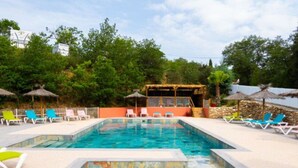 Piscina com espreguiçadeiras e área coberta.