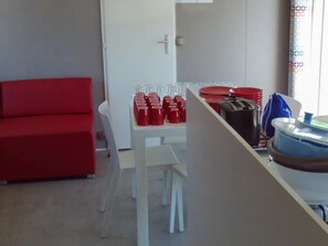 Ein Zimmer mit einem roten Sofa, einem weißen Tisch mit roten Tassen und Tellern sowie einem blauen Wasserspender.