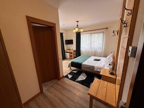 Une chambre à coucher avec un lit, un bureau, une chaise, une télévision et une fenêtre avec des rideaux.