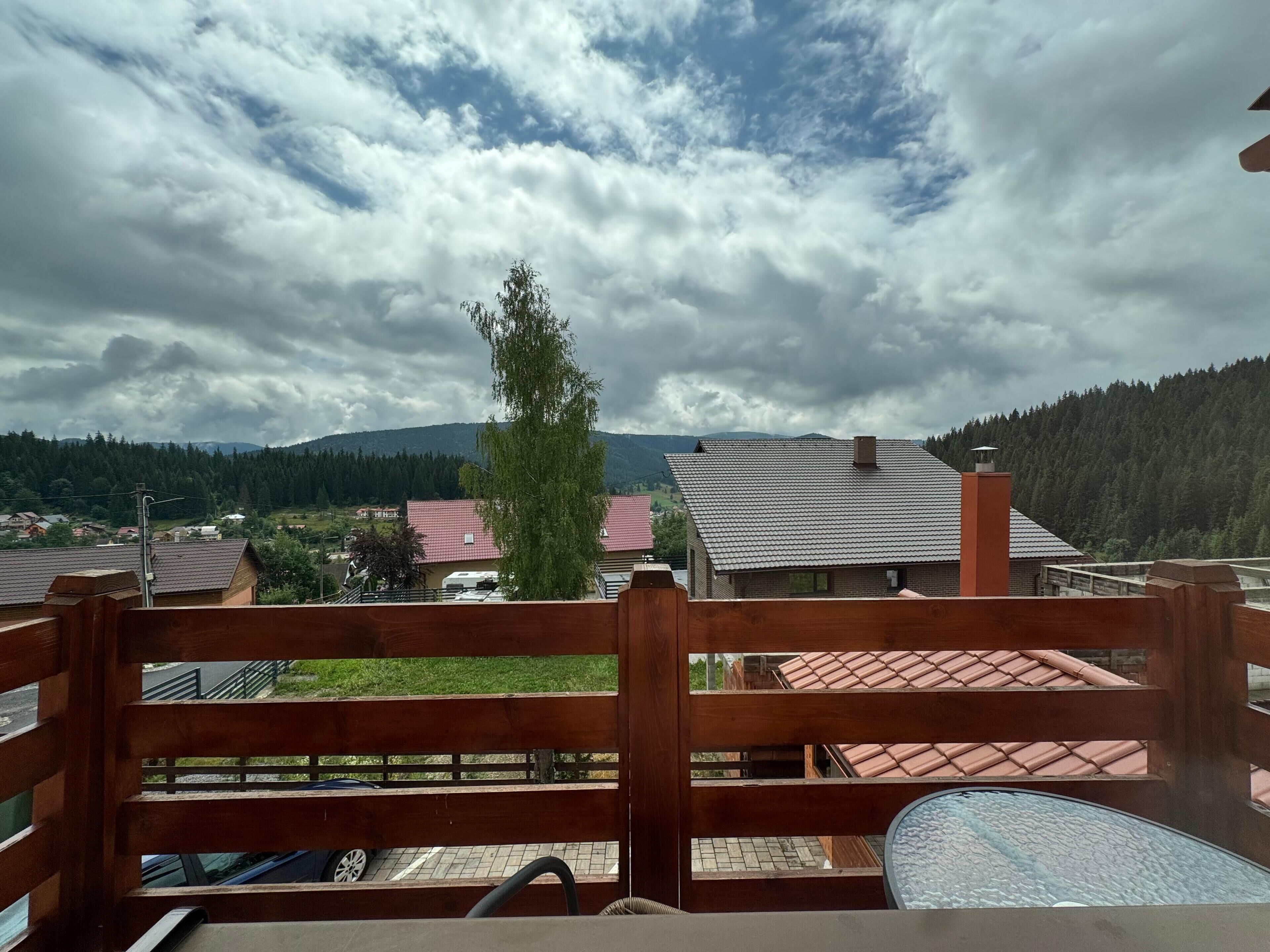 Un balcón con vistas a un pueblo, una valla de madera y una mesa con una silla.