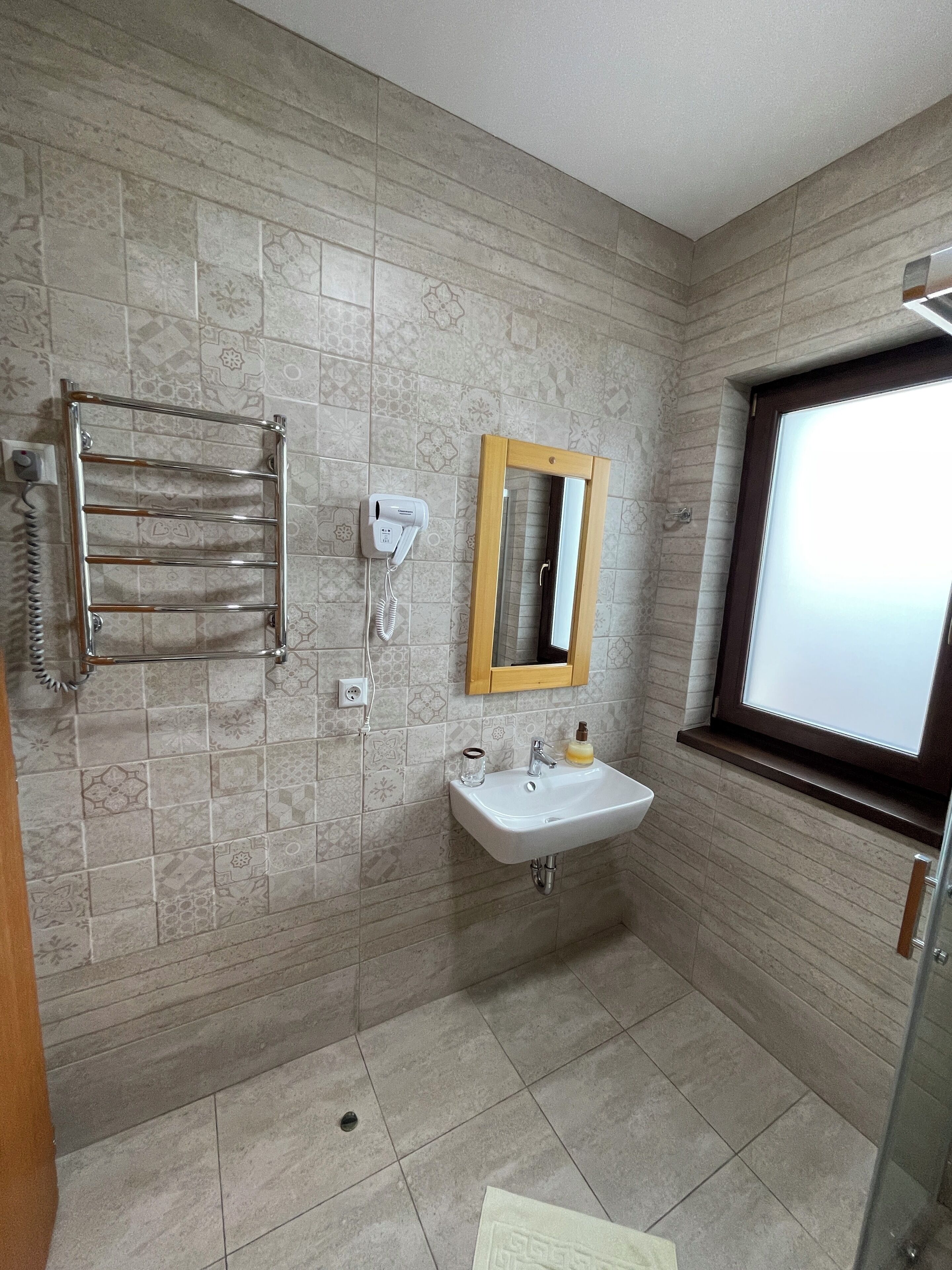 A bathroom with a shower, a sink with a mirror, and a towel rack.