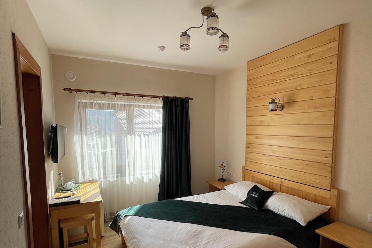 A bedroom with a wooden bed, a desk, and a nightstand.