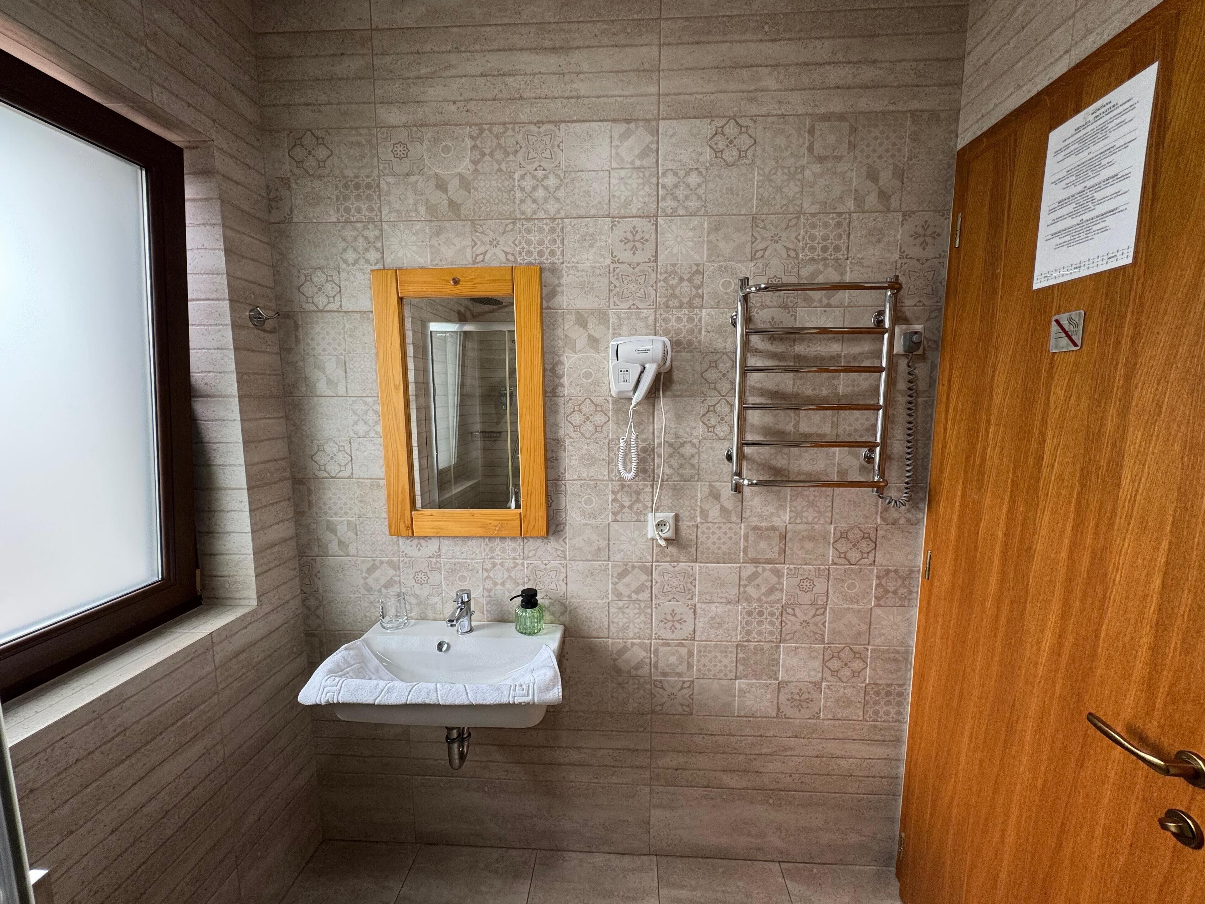 Un baño con lavabo, espejo, toallero y ventana.