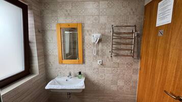 Un baño con lavabo, espejo, toallero y ventana.