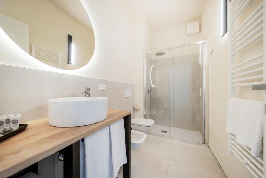 A modern bathroom with a large oval sink, a glass shower enclosure, and a built-in towel rack.
