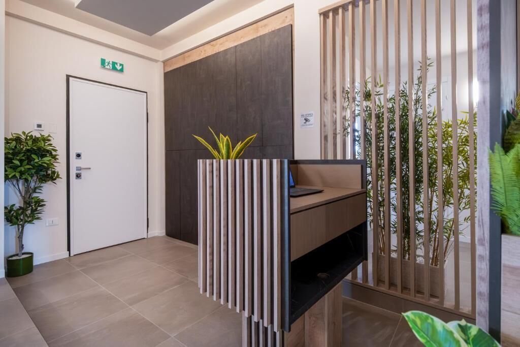 A reception area with a modern design, including a reception desk, a potted plant, and a bamboo screen.