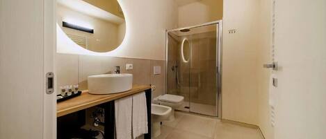A modern bathroom with a round mirror, a sink, a toilet, and a shower.