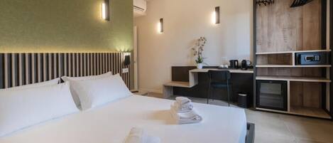 A modern hotel room with a large bed, a desk, and a wardrobe.