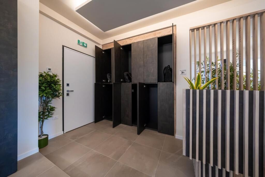 A modern reception area with a closed door, a potted plant, and a striped partition.