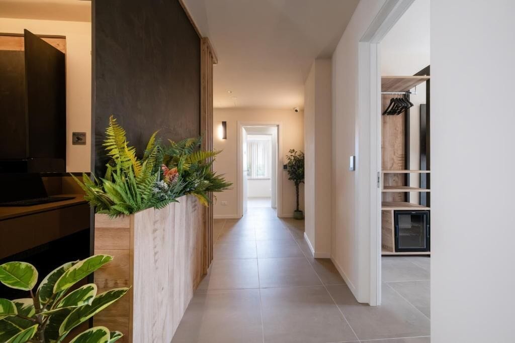 A hallway with a wooden cabinet on the left, a plant, and a door at the end.