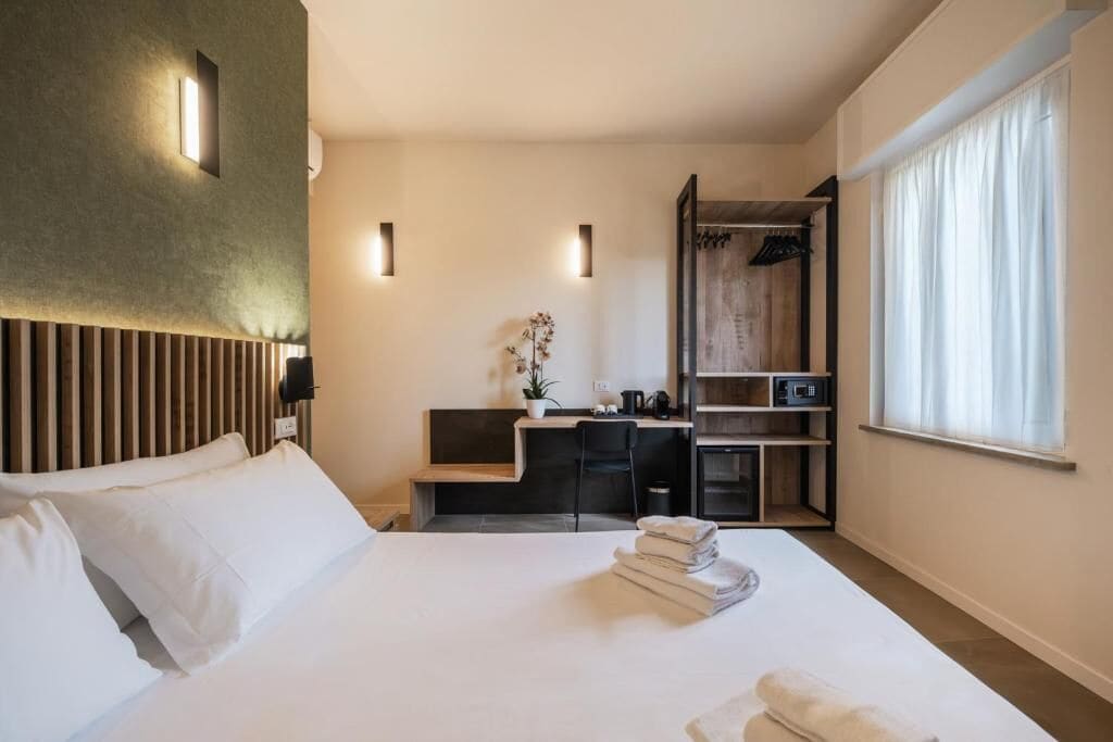 A hotel room with a bed, a desk, a wardrobe, and a window.