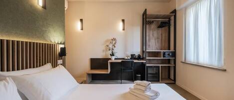 A hotel room with a bed, a desk, a wardrobe, and a window.