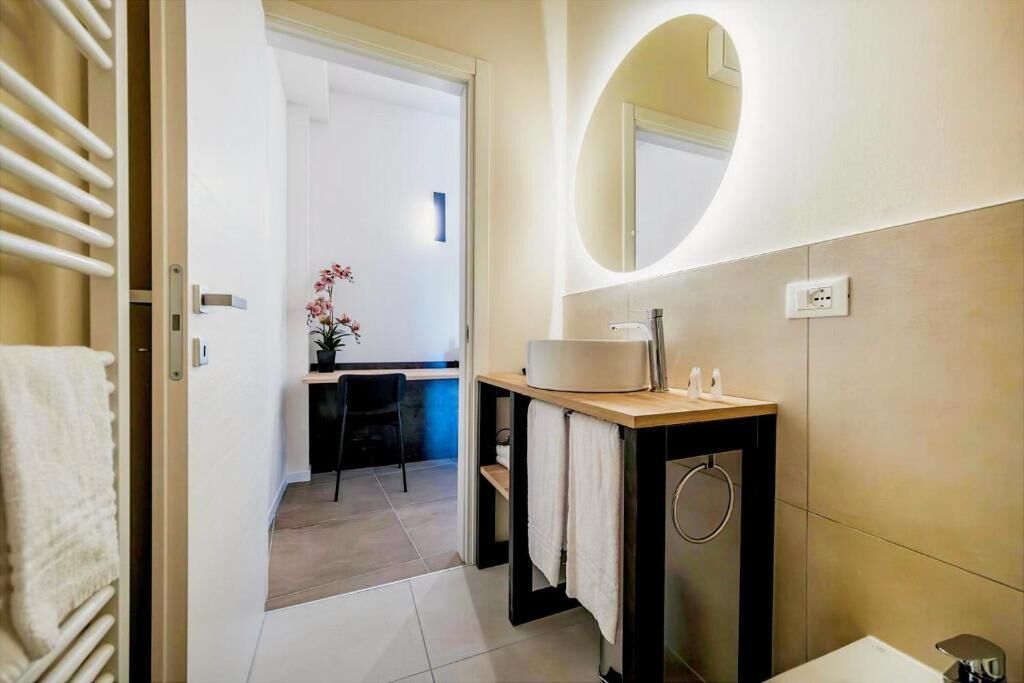 A modern bathroom with a sink, mirror, and towel rack.