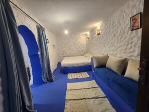 Ein Zimmer mit einem Bett, einem blauen Sofa und einem Teppich mit Muster.
