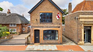 A brick building with a black door and a window with a flag.