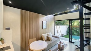Una sala de estar moderna con un sofá, una mesa redonda y vistas a una piscina.