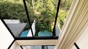 Un interior moderno con techo de vidrio, una piscina azul y una planta en maceta.