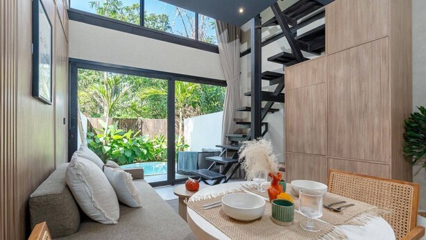 Un interior moderno con zona de comedor, sofá y escalera.